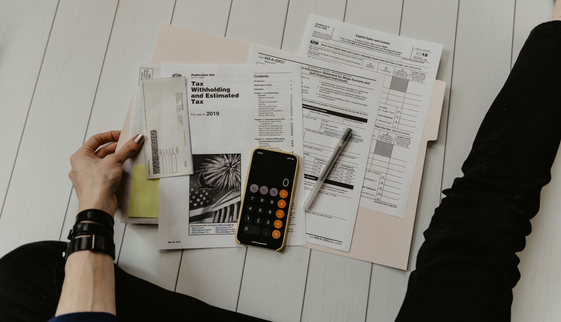 Persona revisando formularios de impuestos con una calculadora (foto de referencia)