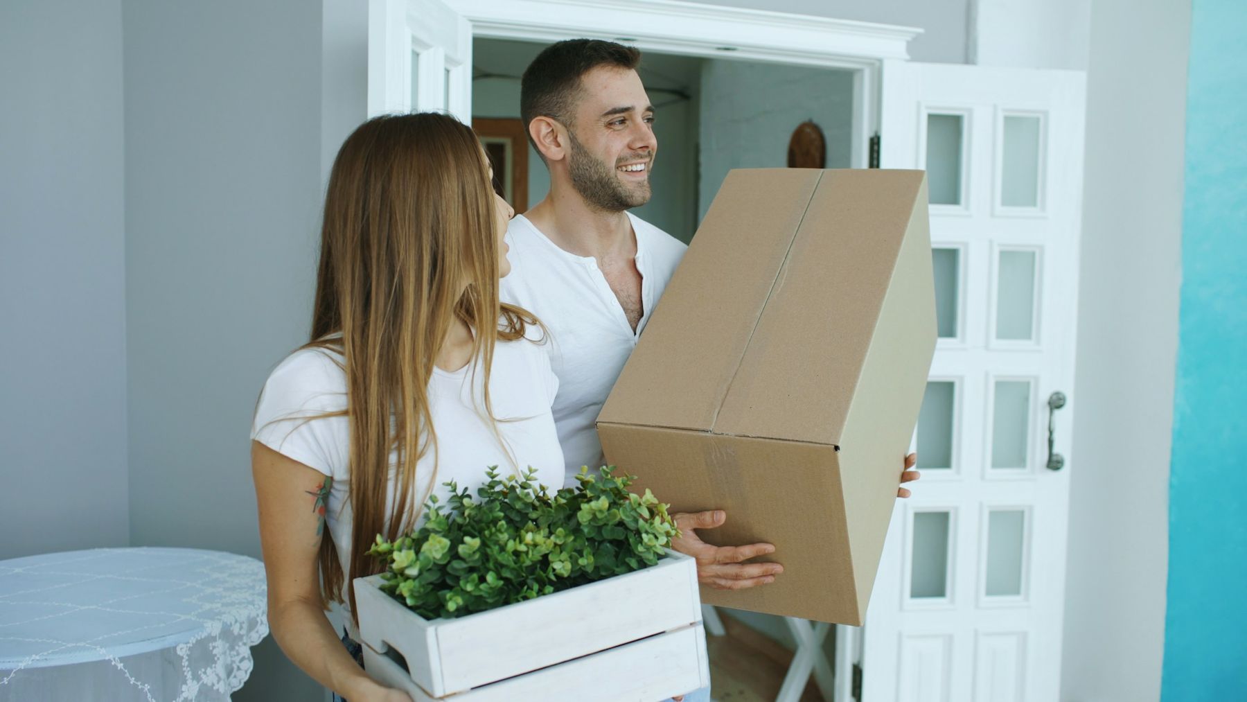 Pareja sonriente con cajas de mudanza en la puerta de su nueva casa
